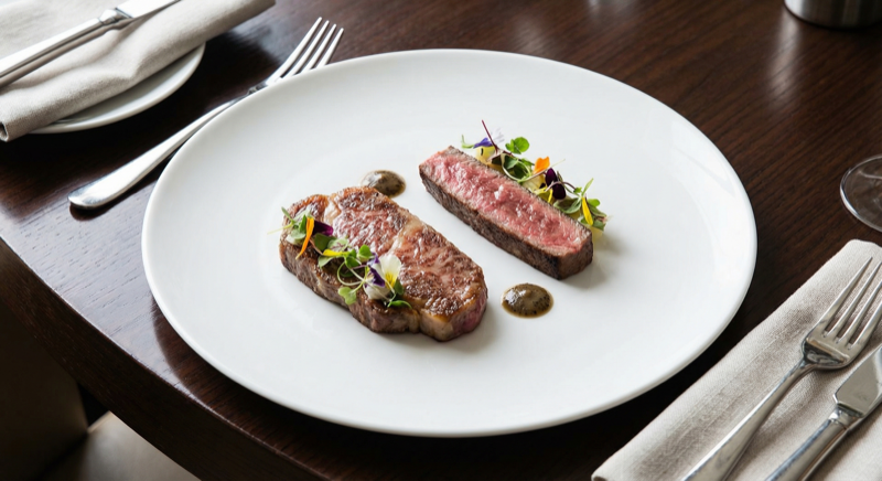 Two different wagyu steaks side by side on elegant plate for comparison - AI generated